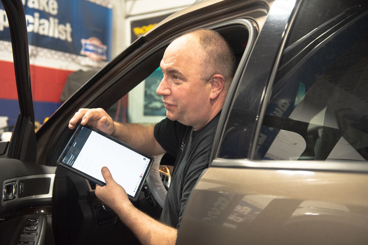 Urban Automotive technician performing a Digital Vehicle Inspection on a tablet in Oakville